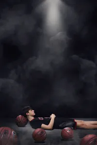 High School senior laying on basketball in gym for senior portrait
