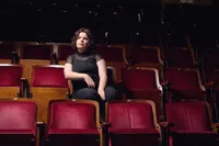 Theatre senior portrait of student seated in red velvet theater seat with cinematic mood