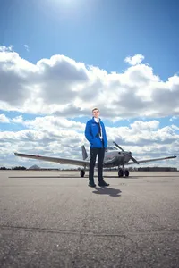 high school senior posing in front of an airplane that he pilots