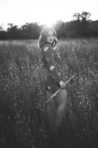 Teen with Flute posing for senior portrait in field in Minnesota with backlight in black and white