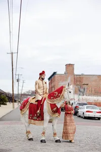 Man in traditional attire riding a decorated horse on an urban street.