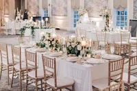 Elegant wedding reception setup with floral centerpieces and gold chairs.