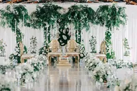 Elegant wedding venue decorated with white flowers and green foliage, featuring ornate chairs and floral arrangements.Elegant wedding venue decorated with white flowers and green foliage, featuring ornate chairs and floral arrangements.
