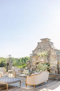 Elegant outdoor seating area with stone fireplace and a view of green fields.