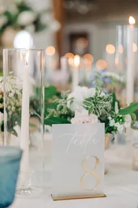 Elegant wedding table setting with a number 8 sign, candles, and floral arrangements.