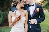 Bride and groom smiling and looking at each other, with the bride showing henna on her hands, suggesting a cultural fusion wedding.