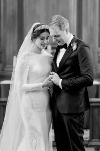 Bride and groom holding hands in a wedding ceremony, captured in black and white photography.