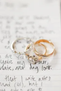 Two wedding rings atop a handwritten love note.
