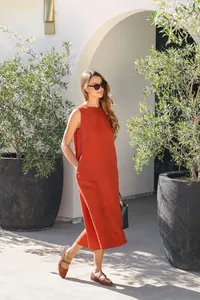 Terracotta linen dress framed by an arched entry and potted olive trees