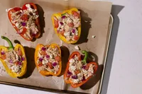 Mini bell peppers stuffed with Natural Catch albacore, feta, tomato, and red onion on a parchment-lined sheet pan