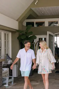 Couple walking hand in hand out of the lobby entrance at L’Auberge Del Mar in linen and an embroidered sundress, guest arrival photography