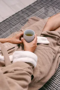 Guest in a plush spa robe resting on a lounger with a cup of green tea between treatments at Spa L’Auberge
