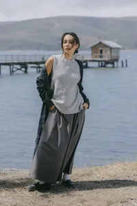 Grey sleeveless knit and wide grey skirt with a plaid overshirt carried at the shoulder