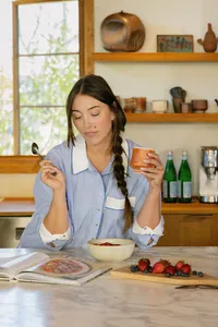 Woman with breakfast and coffee at a marble kitchen island, nutrition vertical