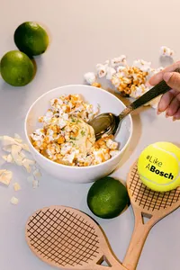 Overhead of a finished popcorn dish styled with limes and wooden rackets