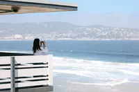 Guest looking through binoculars from an oceanfront deck across Monterey Bay