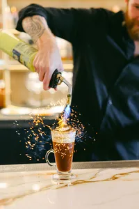 Bartender torching a spiced coffee cocktail in a burst of sparks at the bar at L’Auberge Del Mar, hotel bar and cocktail photography