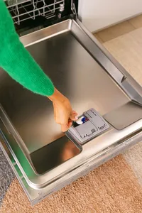 Detergent tab being placed in a Bosch dishwasher dispenser, close detail