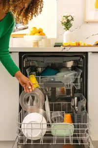 Hand placing a glass into the upper rack of a Bosch dishwasher