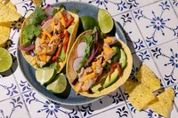 Fish tacos with Natural Catch spicy chili tuna, radish, red pepper, avocado, and lime on blue and white tile