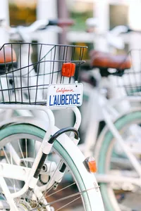 White beach cruiser bikes with baskets and a California L’Auberge license plate, ready for guests to ride into Del Mar village