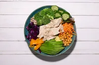 Superfood bowl with Natural Catch albacore, quinoa, broccoli, red cabbage, chickpeas, and avocado on white wood