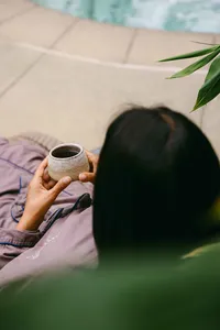 Overhead of a guest holding tea beside the pool