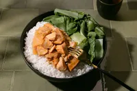 Natural Catch teriyaki coho salmon over white rice with bok choy in a dark bowl on sage green tile