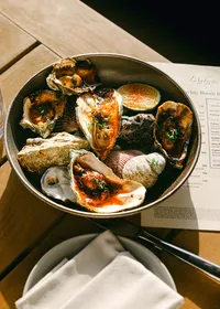 Grilled oysters with charred lime served in a pan beside the Living Room Bar menu at L’Auberge Del Mar, hotel bar food photography