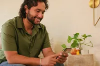 Man on his phone at home during a telehealth check-in