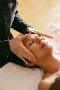 Esthetician massaging a guest’s temples during a gold eye-mask facial at Spa L’Auberge, luxury resort spa campaign photography
