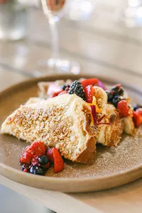 French toast with powdered sugar, fresh berries, and edible flowers served with champagne at Adelaide, hotel brunch and food photography