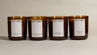 Four lit Soft Current coconut soy candles (Pearfection, Fairgrounds, Petal Promenade, and Aperitivo Hour) lined up on a warm neutral backdrop. E-commerce candle photography by Chelsea Loren.
