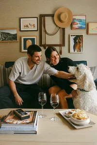 Couple with their dog in a guest room, wine and small plates on the table