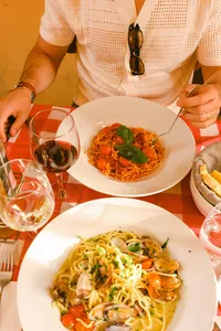Italian food on an outdoor terrace with a glass of wine and red checkerboard tablecloth. France Italy honeymoon by travel food photographer Chelsea Loren.