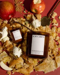 Overhead flat lay of a Soft Current Fairgrounds candle surrounded by red apples, pie crust crumbles, honey, vanilla bean, cardamom, and brown sugar. Food and candle styling by Chelsea Loren.