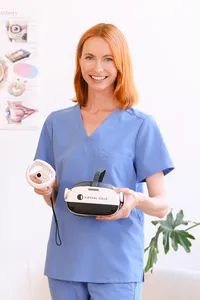 Ophthalmic technician in scrubs holding a Virtual Field VR perimetry headset and controller in an eye clinic