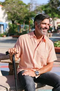 Man in his sixties seated in a park holding a mobility cane, casting real-world mature talent for a mobility device campaign