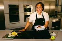 Chef Evelyn Garcia presenting a plated dish at a Bosch induction cooktop