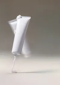 Studio still of a white product tube against a soft grey background
