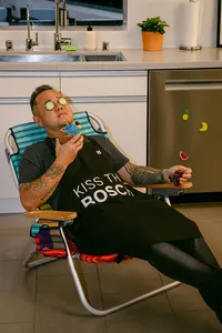 Jet Tila reclining in a lawn chair with cucumber slices over his eyes