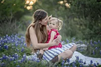 Mom snuggling with child in the bluebonnets during family photo session