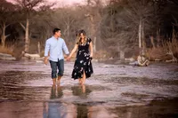 Engagement pictures on the river in Wimberley, with couple holding hands in the water