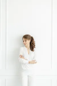Portrait of a woman leaning against the wall in a Dallas TX photography studio with her arms crossed as she looks over her shoulder posing for her boudoir session.