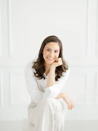 Beautiful in studio headshot photo of a Dallas small business owner sitting on a stool and looking at the photographer smiling.