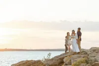 A beautiful family sunset photo as they are posing on rocks holding each other at a local DFW lake for their photographer.