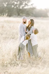 A family photo of a Frisco family posing in an open grassy field.