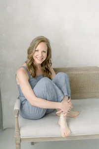 A beautiful photo of a Dallas business woman sitting on a bench at a Dallas photography studio posing for her professional headshots.
