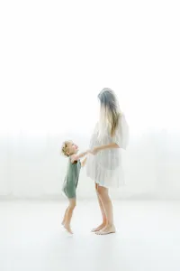 A portrait taken in a DFW photography studio of a pregnant mother dancing around with her toddler son for her maternity session.