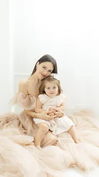 An elegant mommy and me photo taken of a mother and her baby girl sitting on the floor of a Flower Mound photography studio.